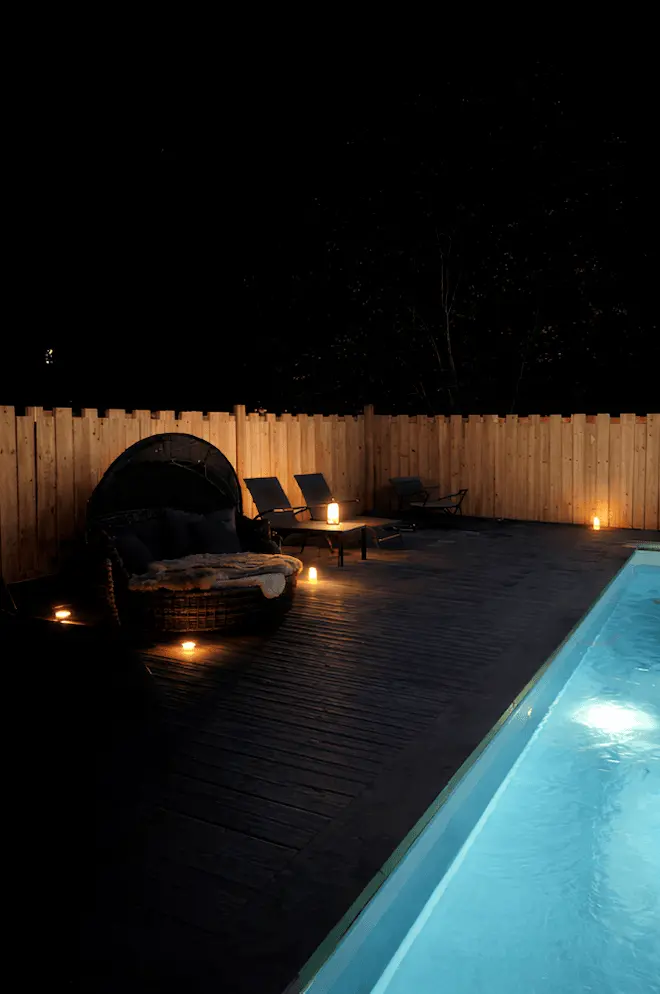 piscine éclairée de nuit avec transats et canapé extérieur